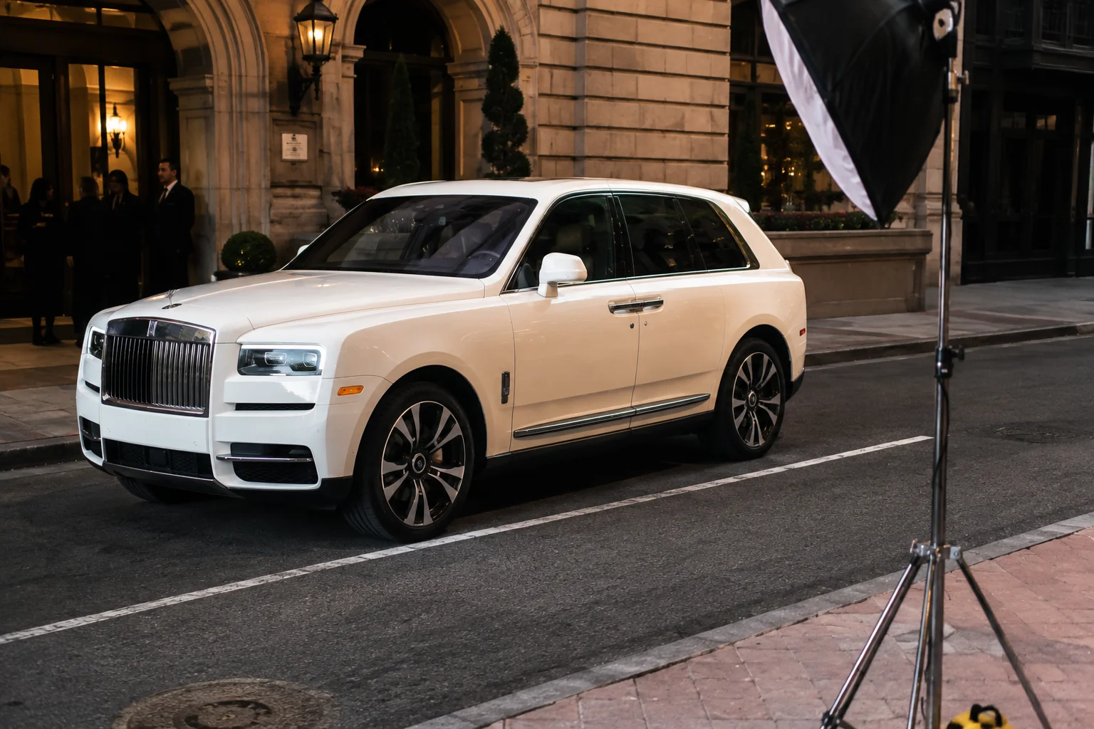 White Rolls-Royce Cullinan on set outside a venue during an evening photoshoot
